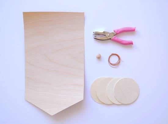 Thin wood pieces, hole punch, button, and wire are all tools being used for this craft.