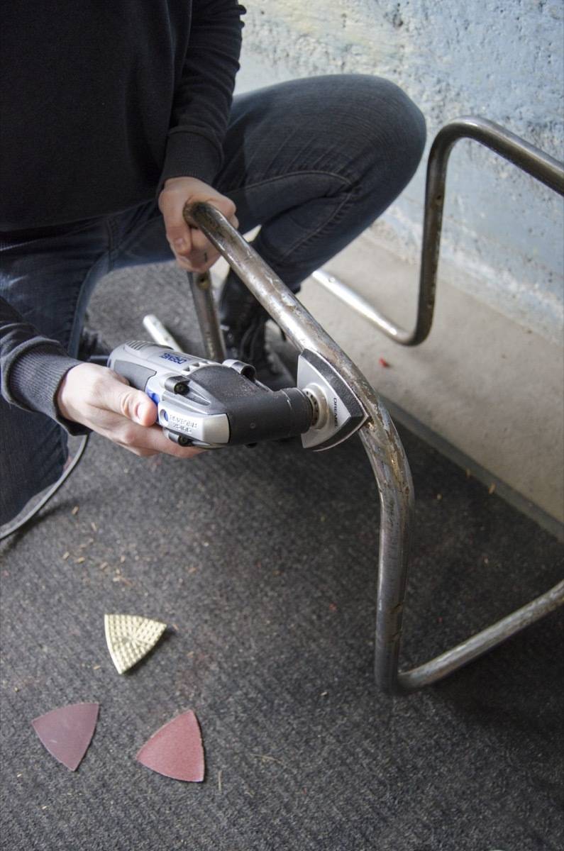 Sanding the metal part of the chair using the Dremel oscillating tool