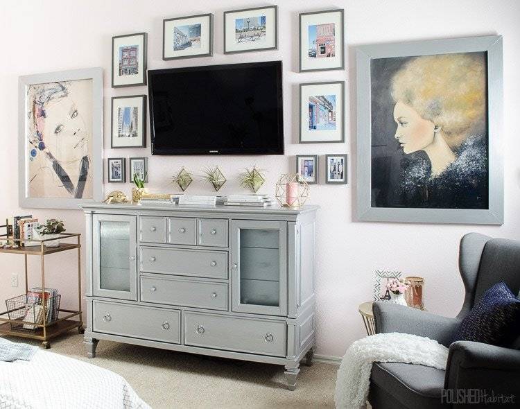 Flat screen television mounted on a wall surrounded by various pictures in a bedroom.