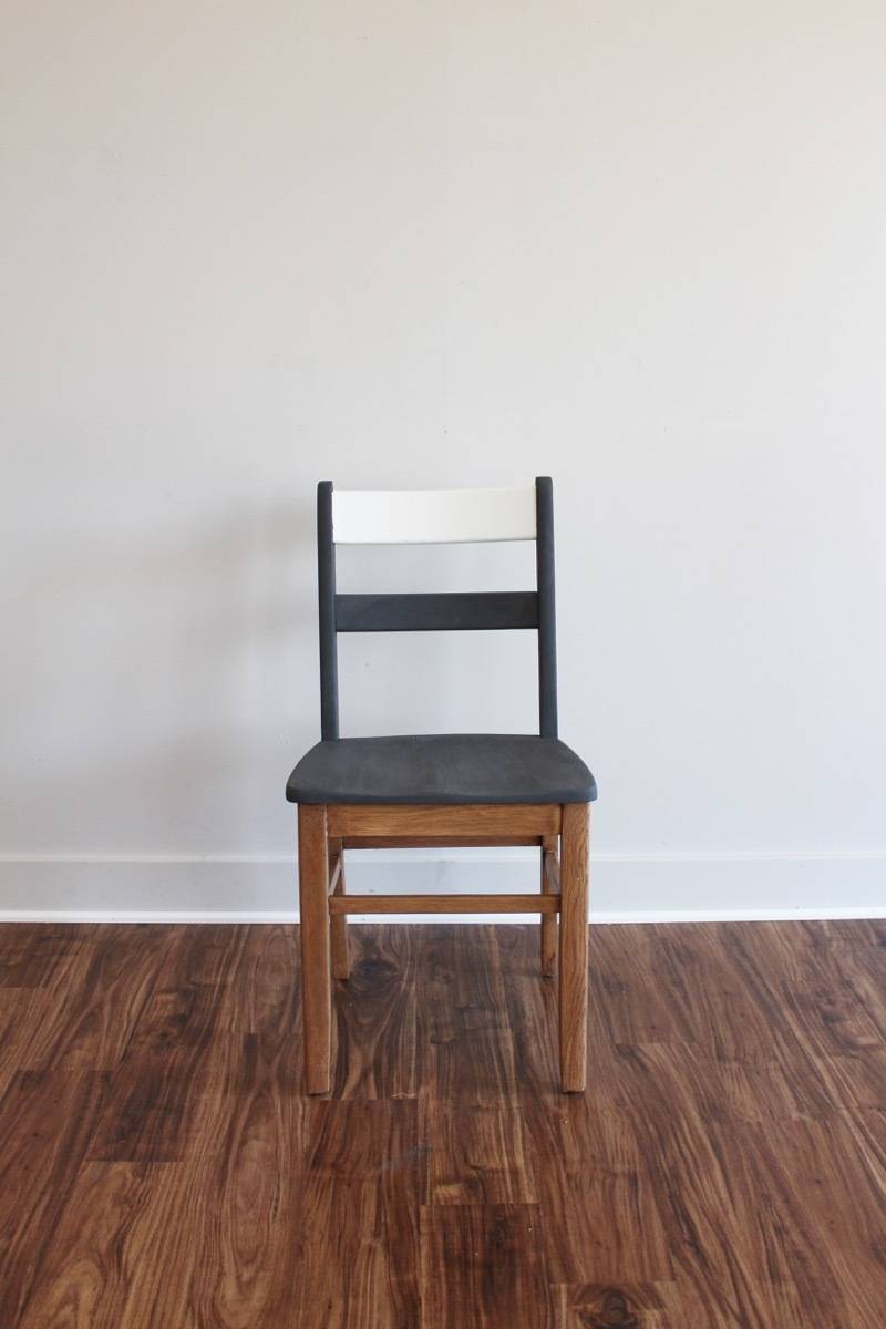 Black, white and wooden combination chair in front of the white wall on the wooden floor.