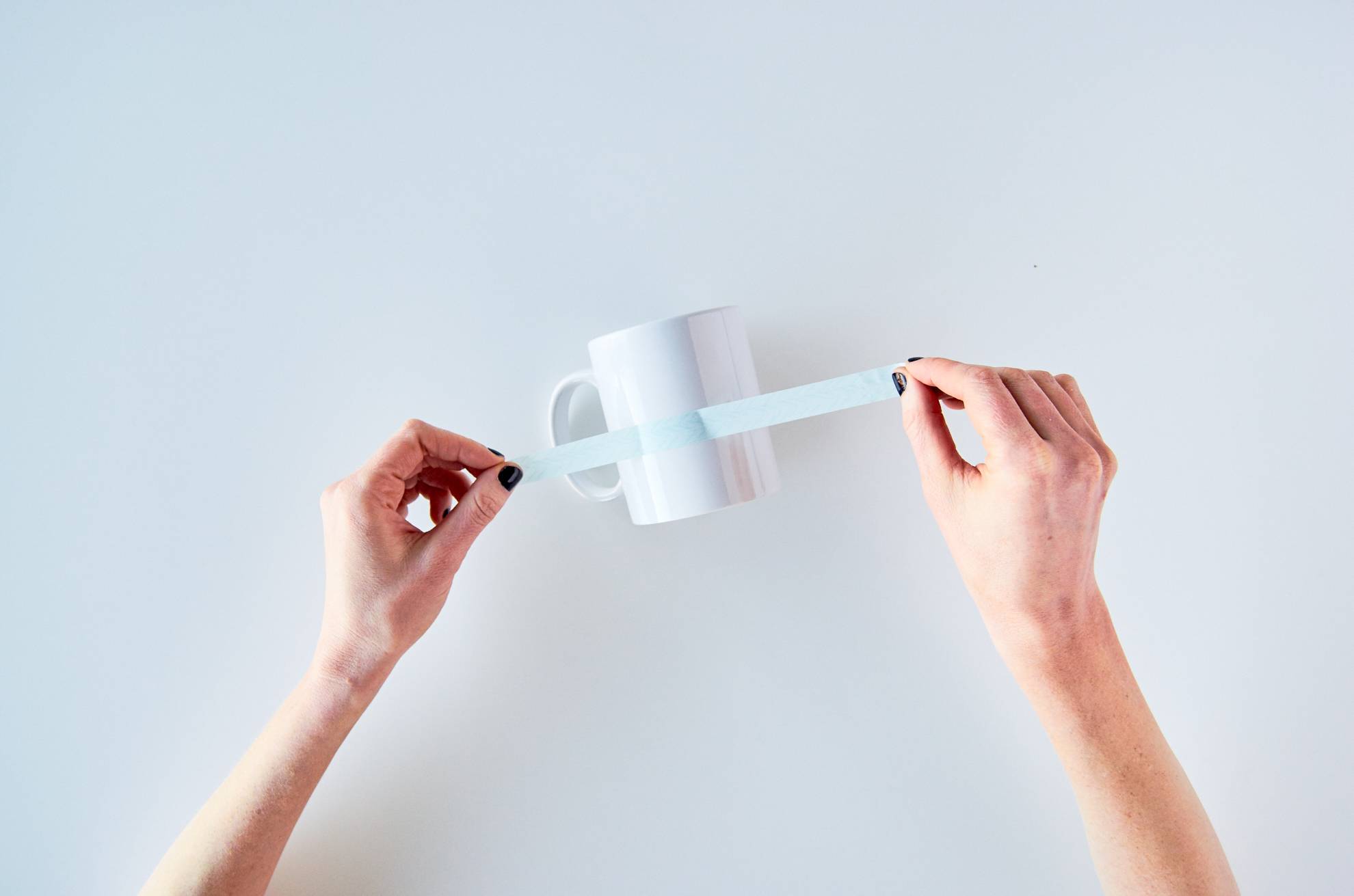 A person putting a sticker on a white mug.