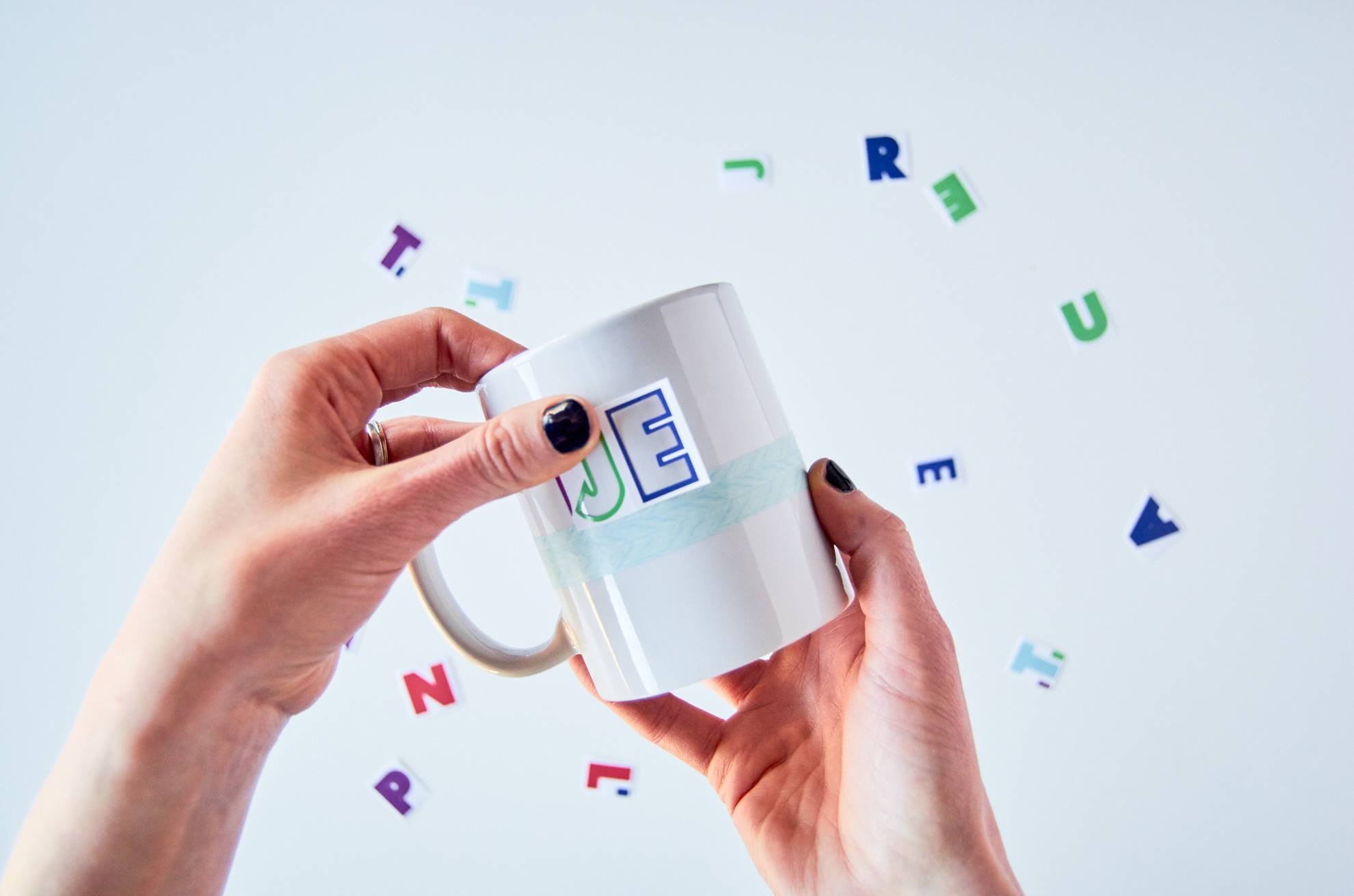 A woman placing lettering on a mug for decoration.