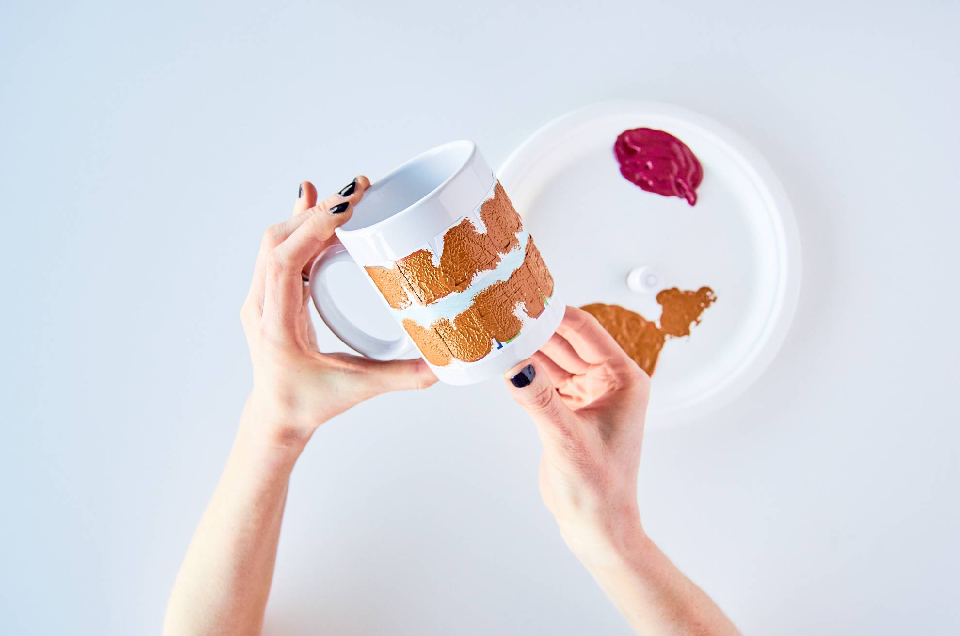 Woman painting a design on a white mug.