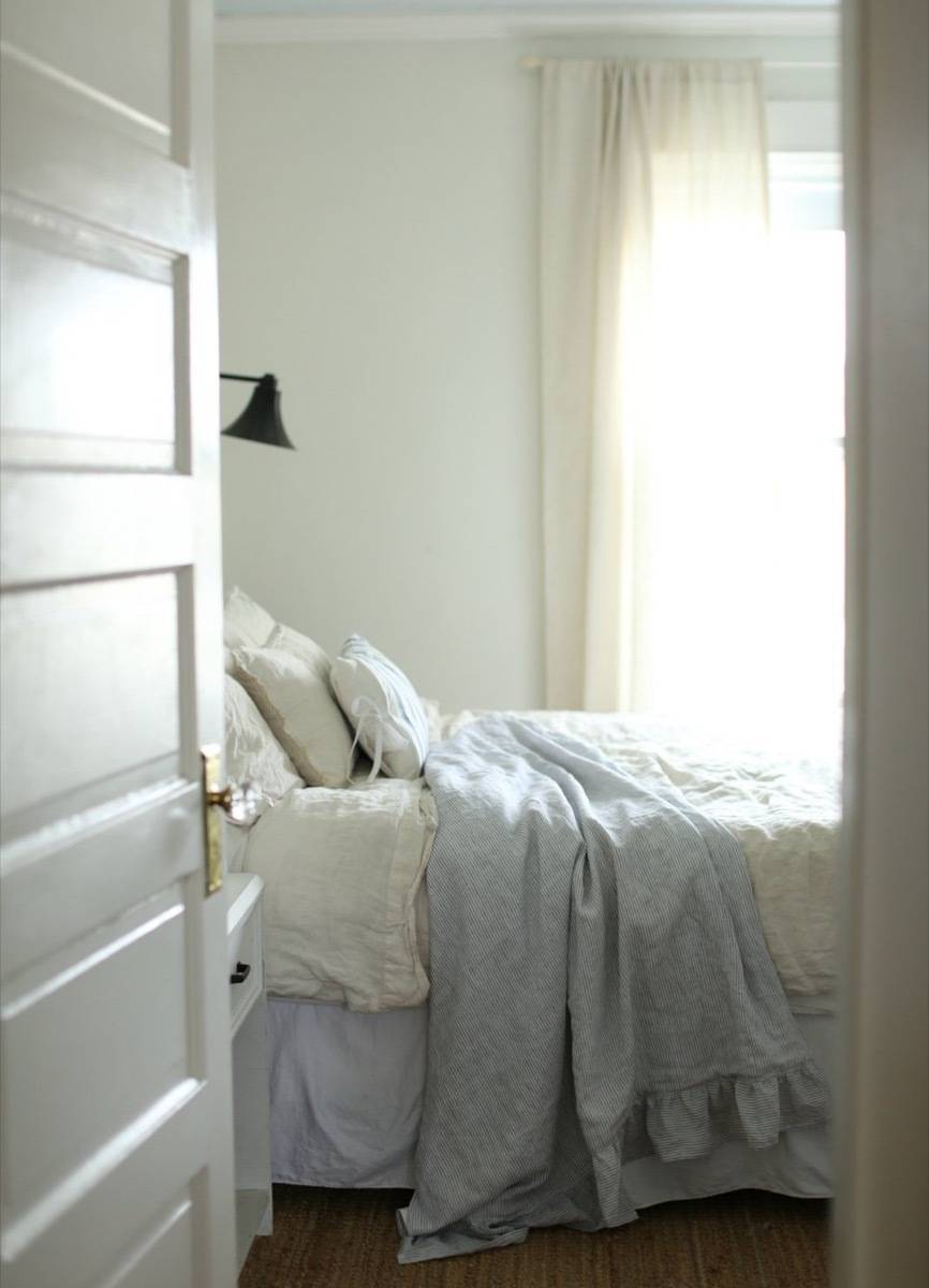 A white door is open to a white bed beyond.