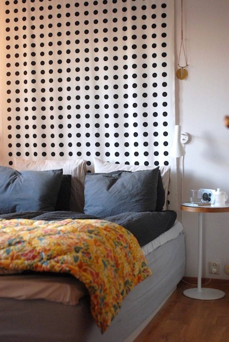 A bed near a white curtain with black dots.