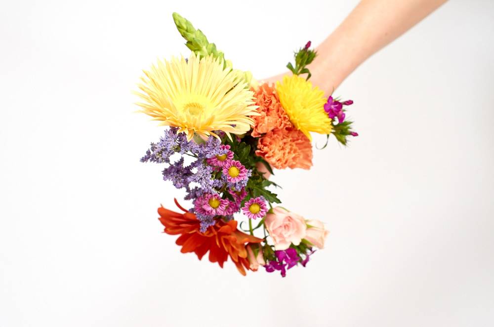 A person holding a bunch of different flower pieces
