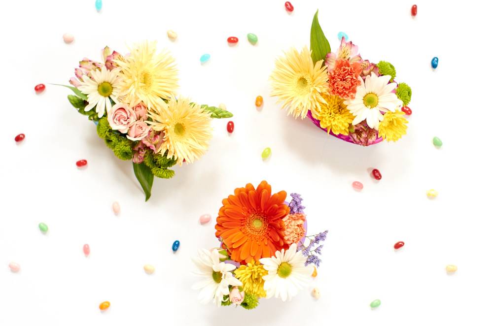 Three separate floral arrangements against a white background and jelly beans scattered throughout.