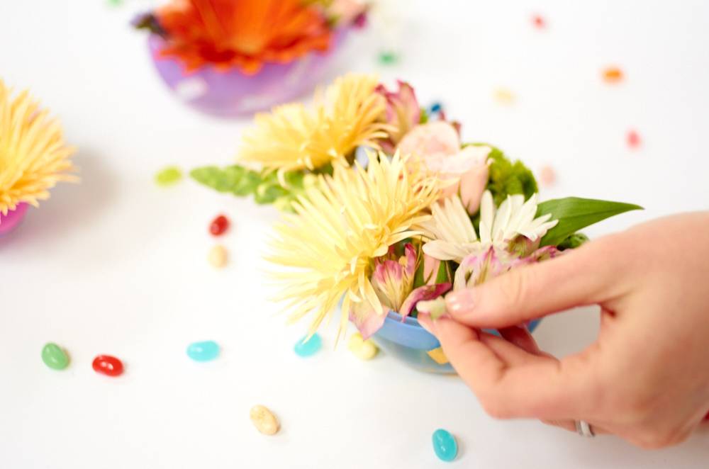 A person works with flowers on a white surface.