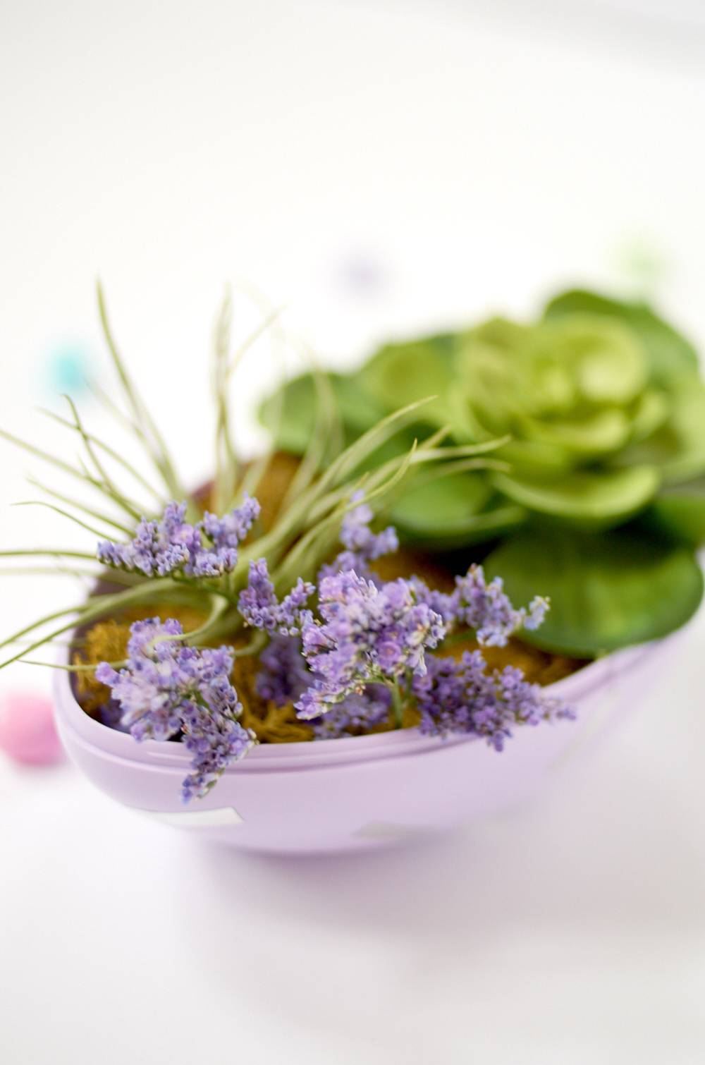 A bowl has purple flowers and green food in it.