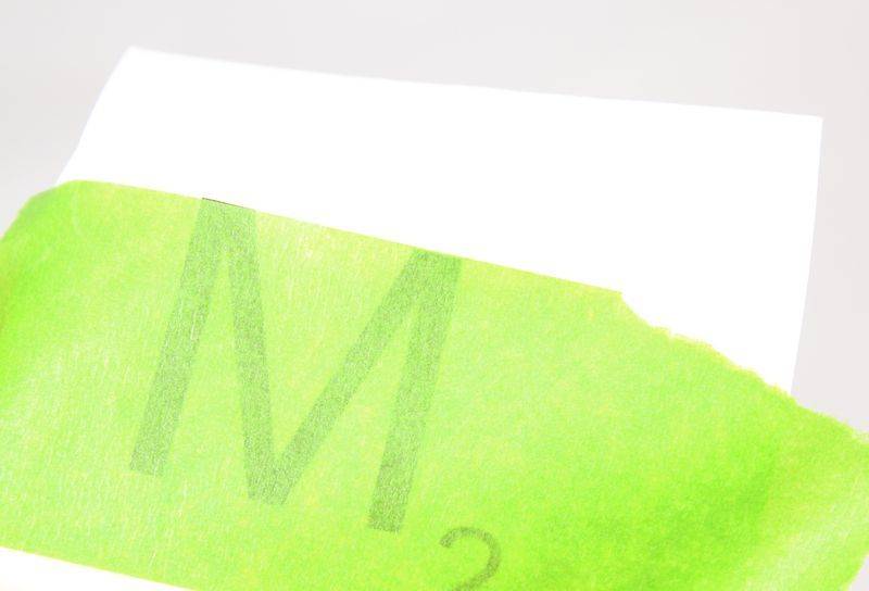 The letter M is written on a green paper.