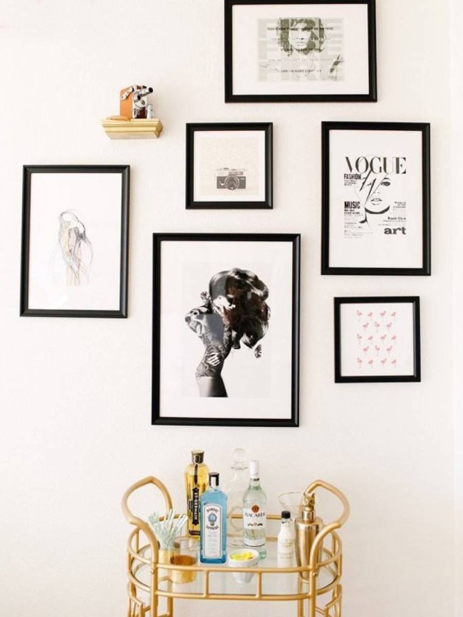 White wall of a home with an interior design of multiple paintings framed on the wall.