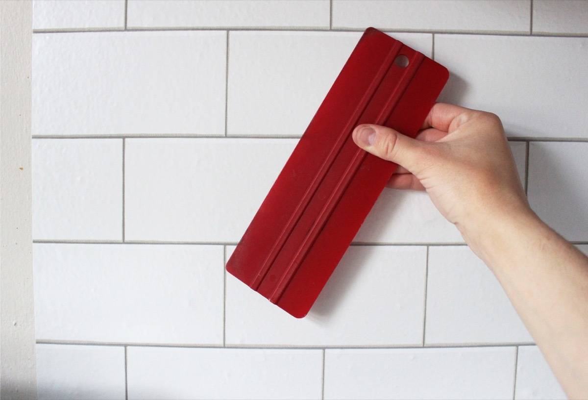 Use a squeegee to install temporary "tile" in your kitchen