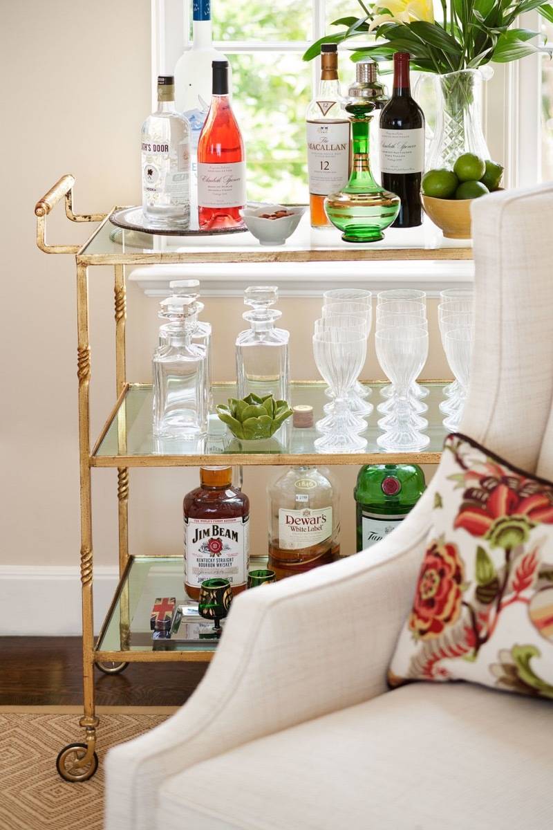 Racks of a table filled with bottles and vase next to a chair.