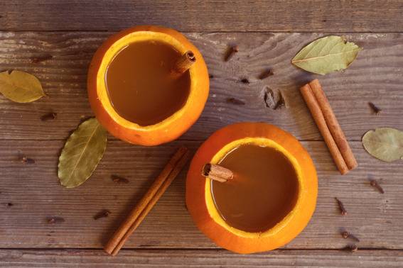 Two open pumpkins have juice and straws in them.