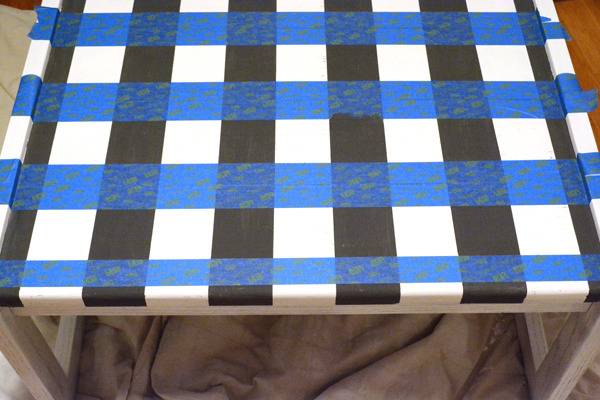 Black and white striped table with blue tape striped across it.