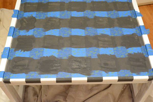 White table sitting on top of a grey sheet with blue tape and black tape on its surface.