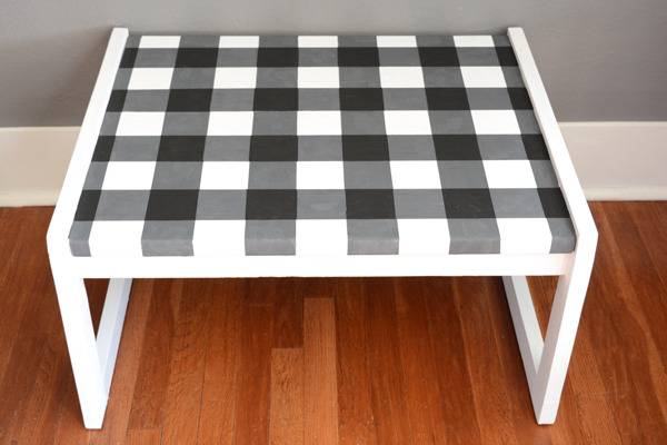 A stool has a grey checkerboard pattern on it.