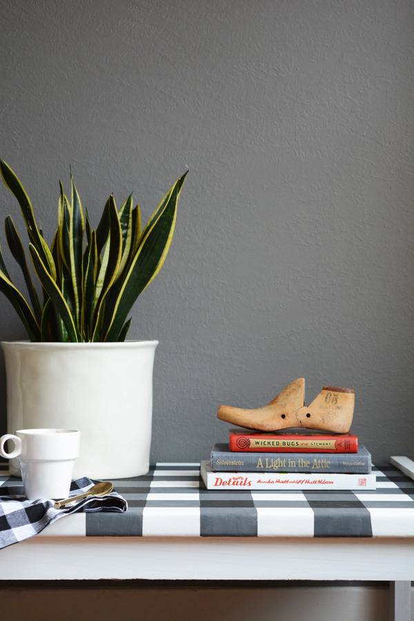 Books and white flower pots adorn a black and white checkered table.