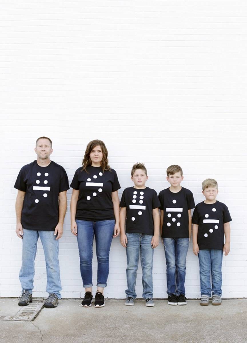 A family of two parents and three kids have on black shirts and stand together.