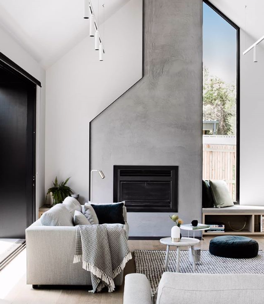 This tall modern cement fireplace and chimney adds drama and luxury to the living room