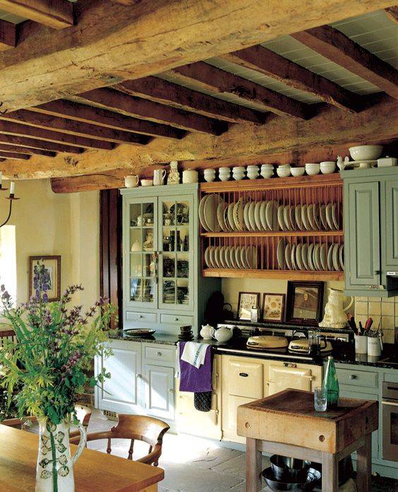 Farmhouse cottage kitchen with soft colors, exposed beam ceiling, brick floors, and original stove. Image from Life on Shady Lane.