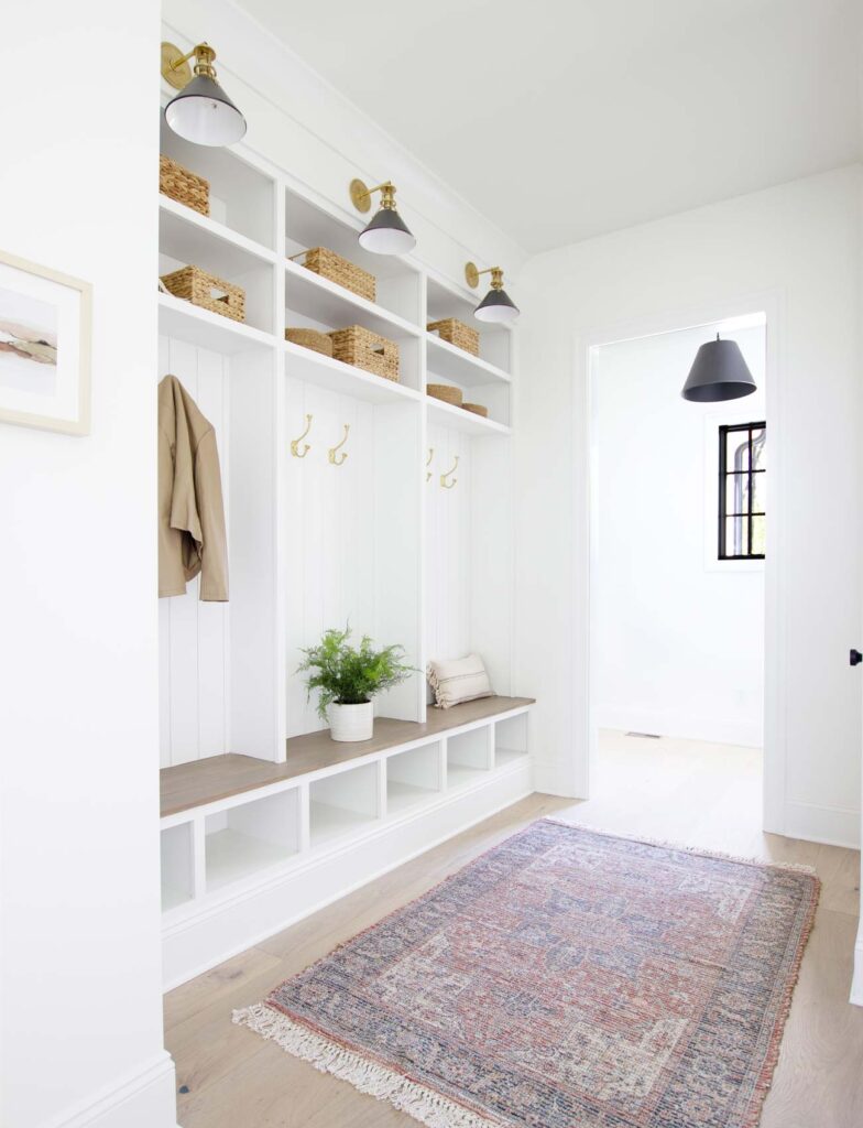 A clean white mudroom with cubbies perfect for storing shoes from Plank and Pillow.