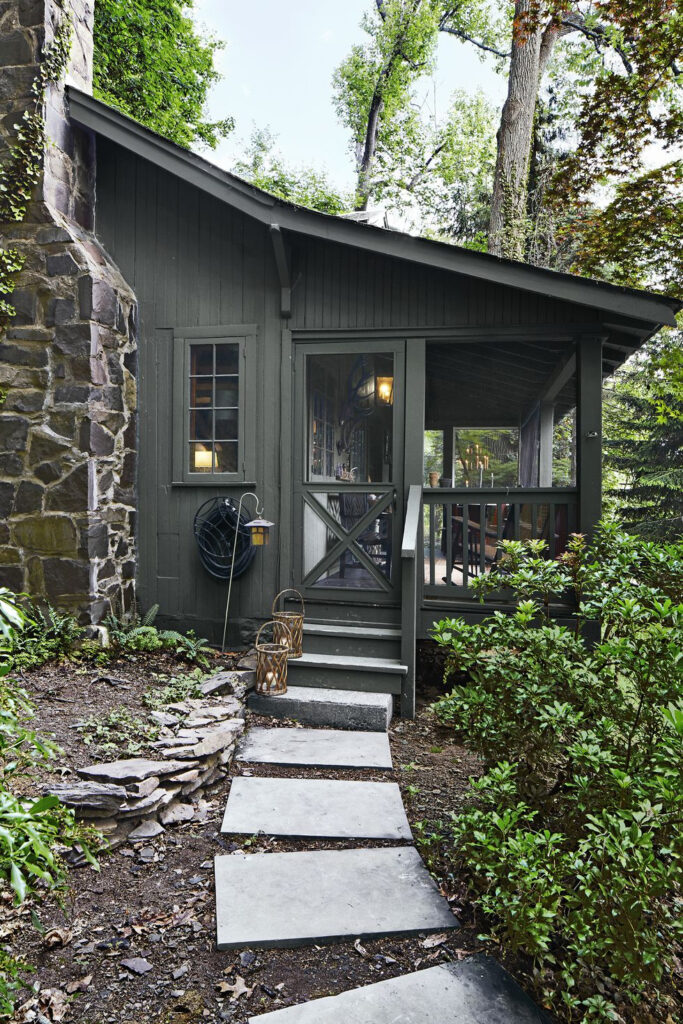 This dark green cabin is from From Country Living, A House Painted a Muted Grey Black with Warm Green Undertones.