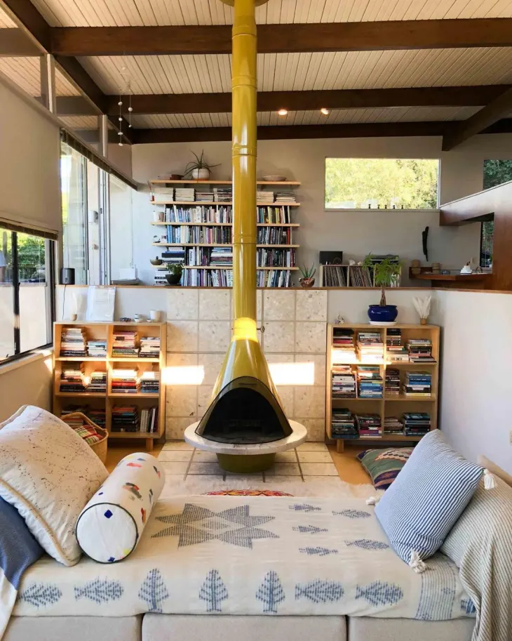 Yellow malm fireplace (or cone fireplace) adds a pop of color to this sunken living space.