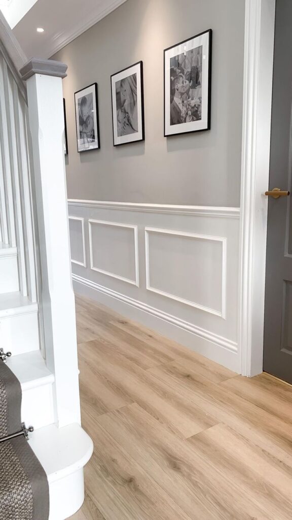 White traditional wainscoting in entryway with staircase and photographs