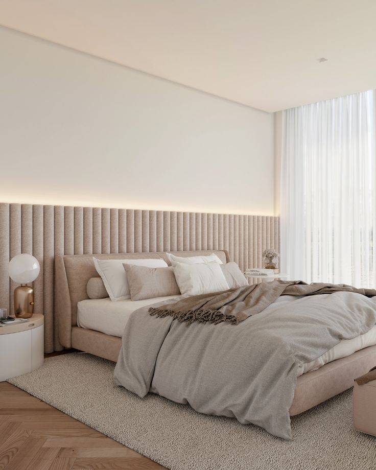 Beige upholstered wainscoting in bedroom, with cream bed featuring a grey throw pillow. 