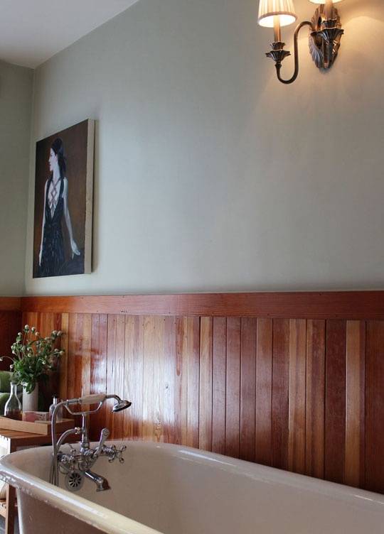 Reclaimed wood wainscoting in bathroom with cream above wood, with picture frame.