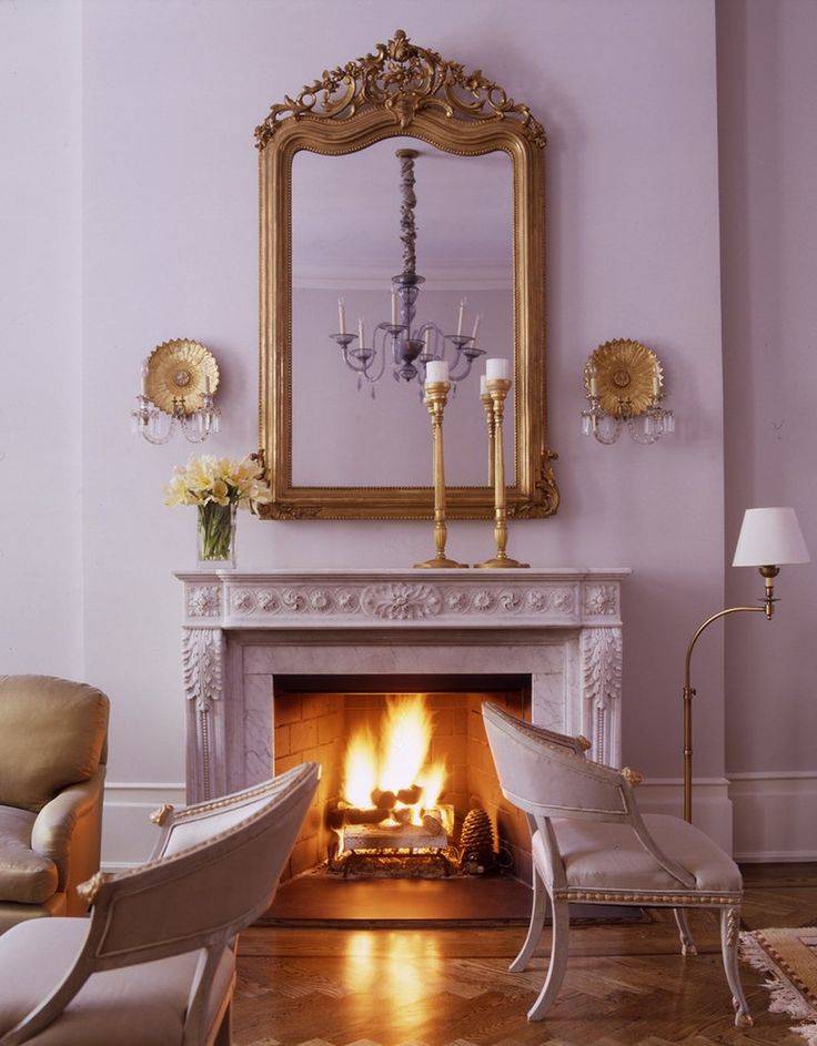 Lavender fireplace with two lavender chairs and gold mirror 