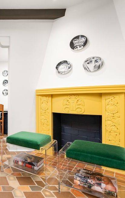 Yellow painted brick fireplace with black bricks inside and two green chairs