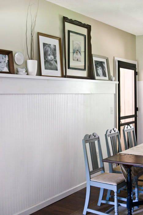 Wainscoting with plate rail holding photos in front of dining table
