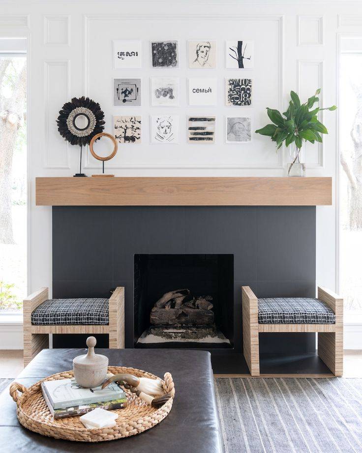 Gray painted fireplace with wood mantel and two gray chairs 