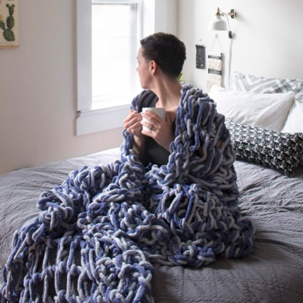 woman wrapped up in her arm knit blanket.