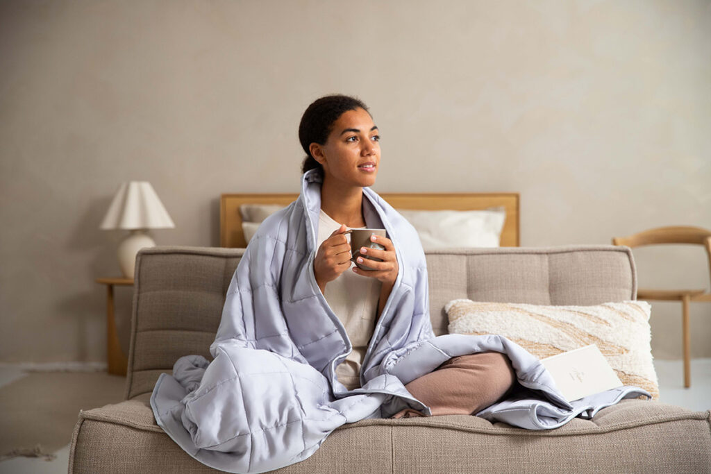 Woman in a cozy blanket, drinking tea.