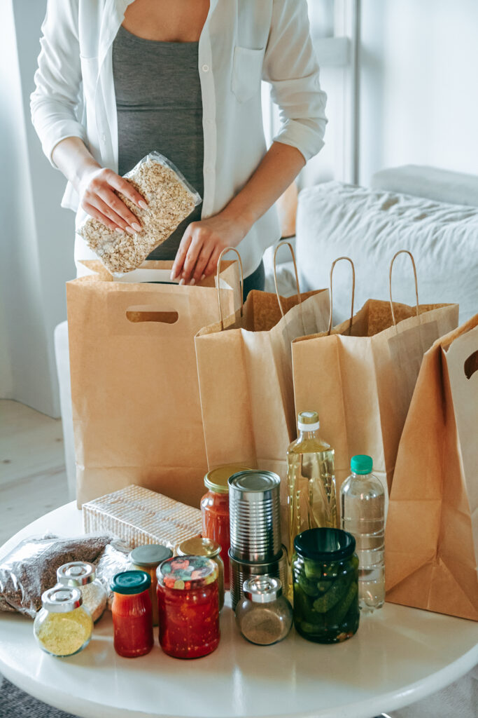 Woman packing food for donation in paper bag.