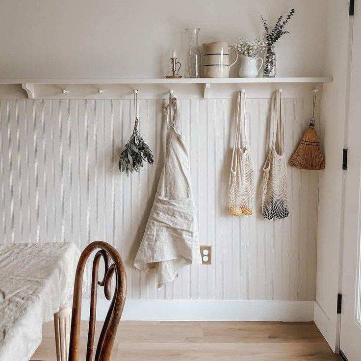 White shelf over beadboard wainscoting with purse and bags hanging