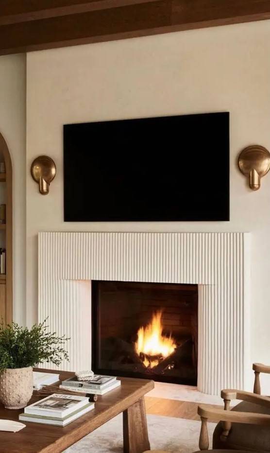 Fluted plaster fireplace with gold accent sconces
