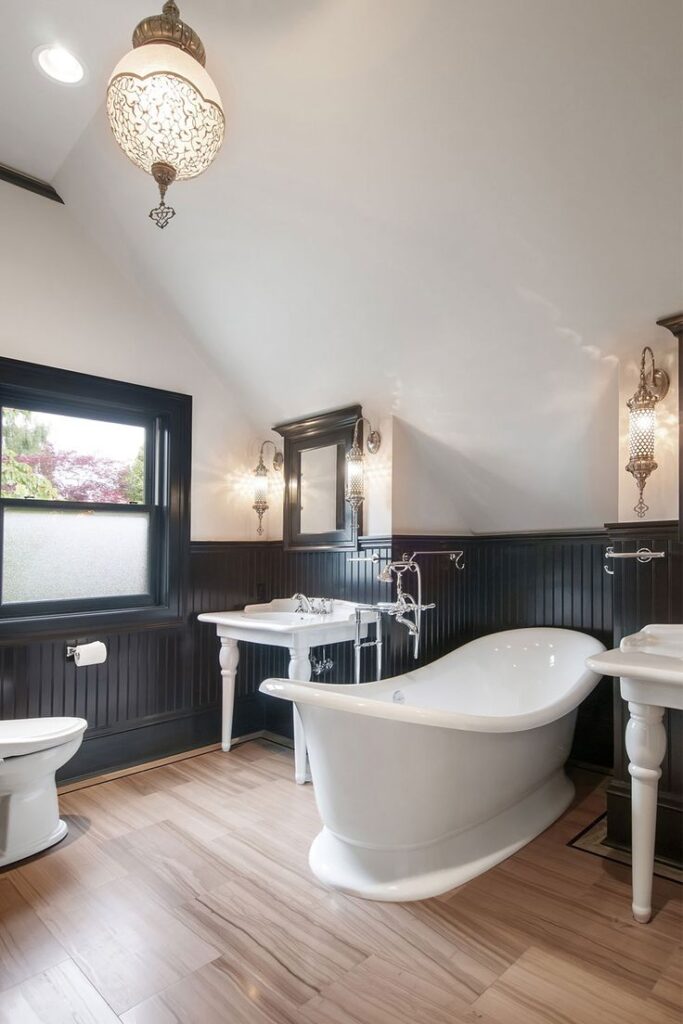 Black bathroom wainscoting on white walls with large tub and brass fixtures 