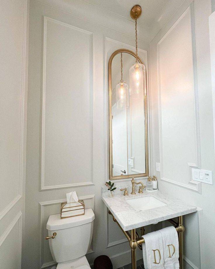 Cream walled bathroom with sink and toilet featuring large mirror on wainscoted wall 