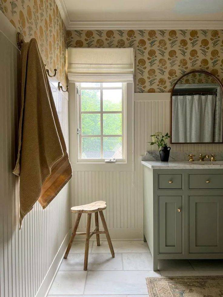 Cream colored bathroom with sage green sink and vertical wainscoting 