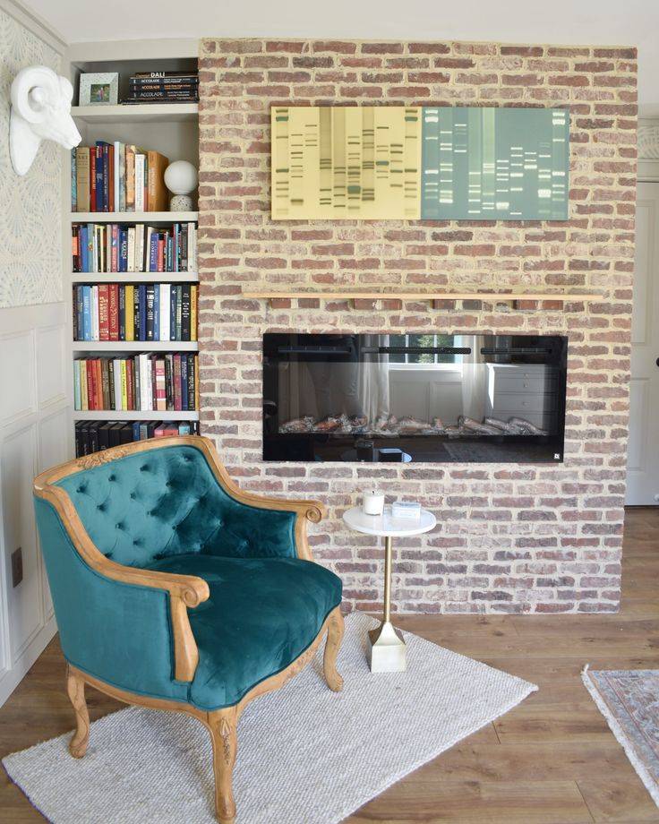 Brick wall behind blue chair, with built-in electric fireplace