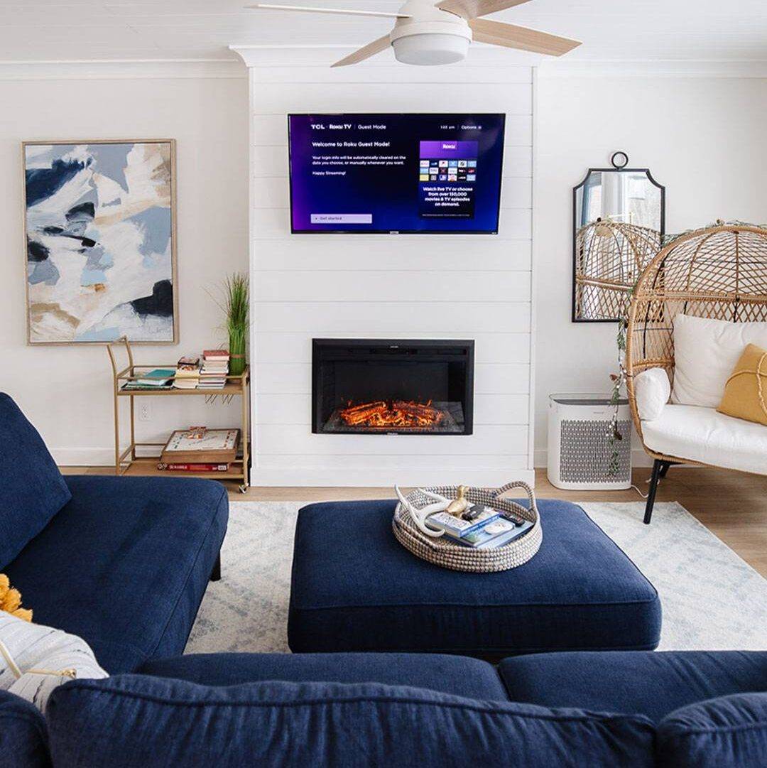 White wall with shiplap in living room. Tv mounted against the wall with built-in electric fireplace.
