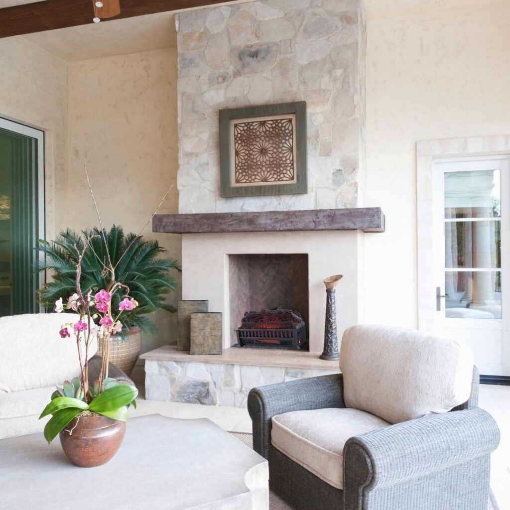 White stucco fireplace with grey marble and tile inside of fireplace. Cream lounge chair.