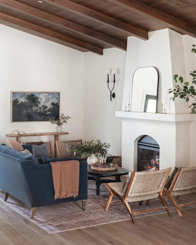 Living room with white stucco fireplace, blue couch and earth tone furniture 