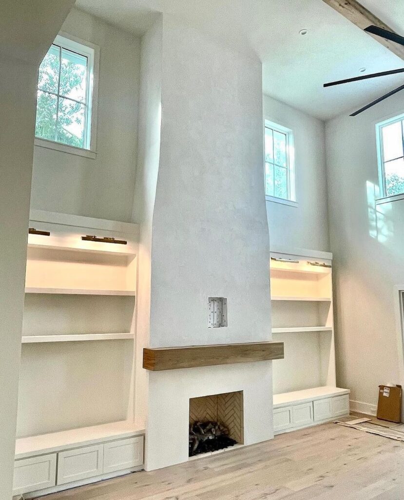 White stucco fireplace with brown wood mantle in living room