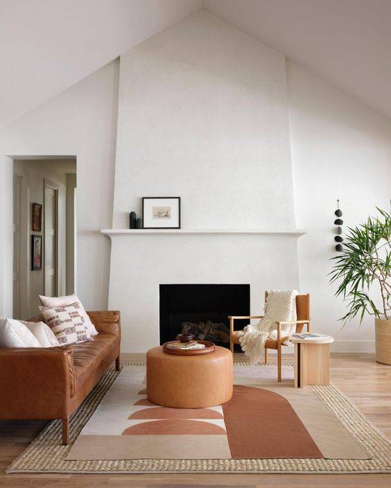 White stucco fireplace with brown couch, rug and table 