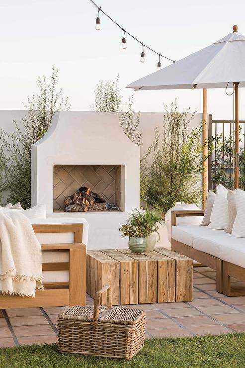 Off white stucco fireplace in outdoor patio with white patio chairs
